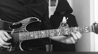 a black and white photo of a man playing an electric guitar